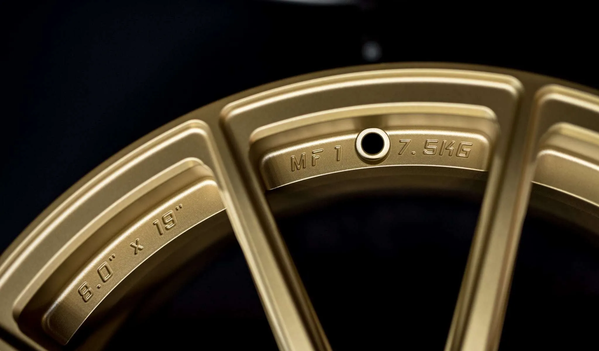 Speichendetail des MF1 in Gold mit Dimensionsgravur